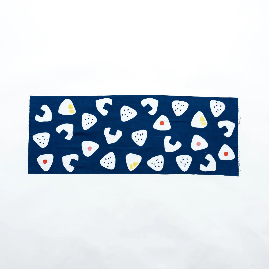 Navy tenugui laid flat, showcasing white rice ball motifs with colorful fillings scattered evenly.