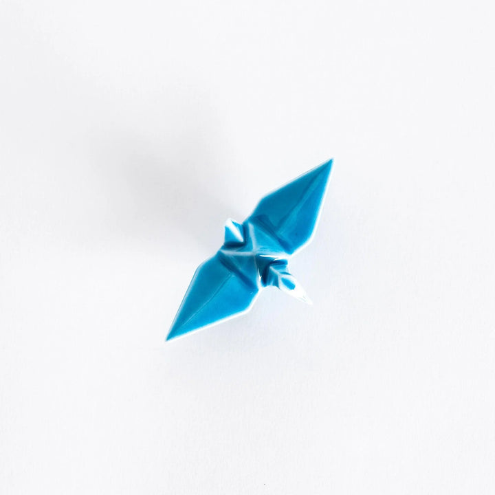 Top view of the light blue ceramic crane-shaped chopstick rest on a white surface.