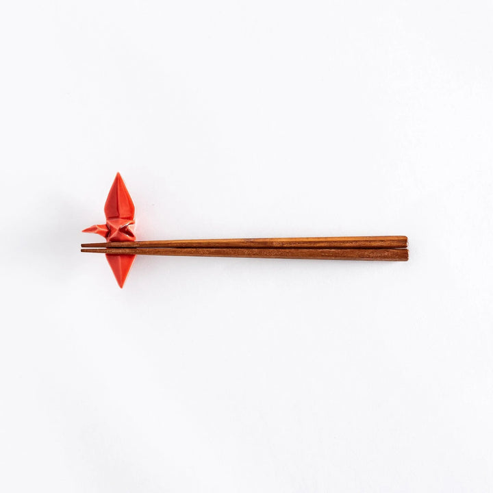 Wide view of chopsticks resting on the red ceramic crane-shaped chopstick rest.
