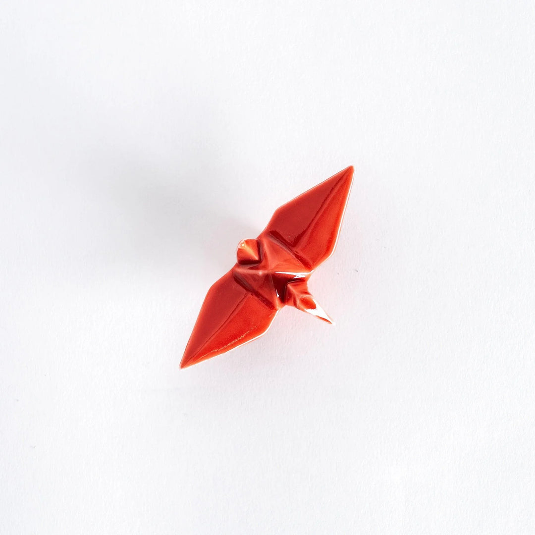 Top view of the red ceramic crane-shaped chopstick rest on a white surface.