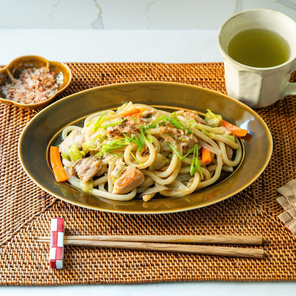Sleek, dark brown or olive colored oval dinner plate with a glossy finish, simple and minimalist.