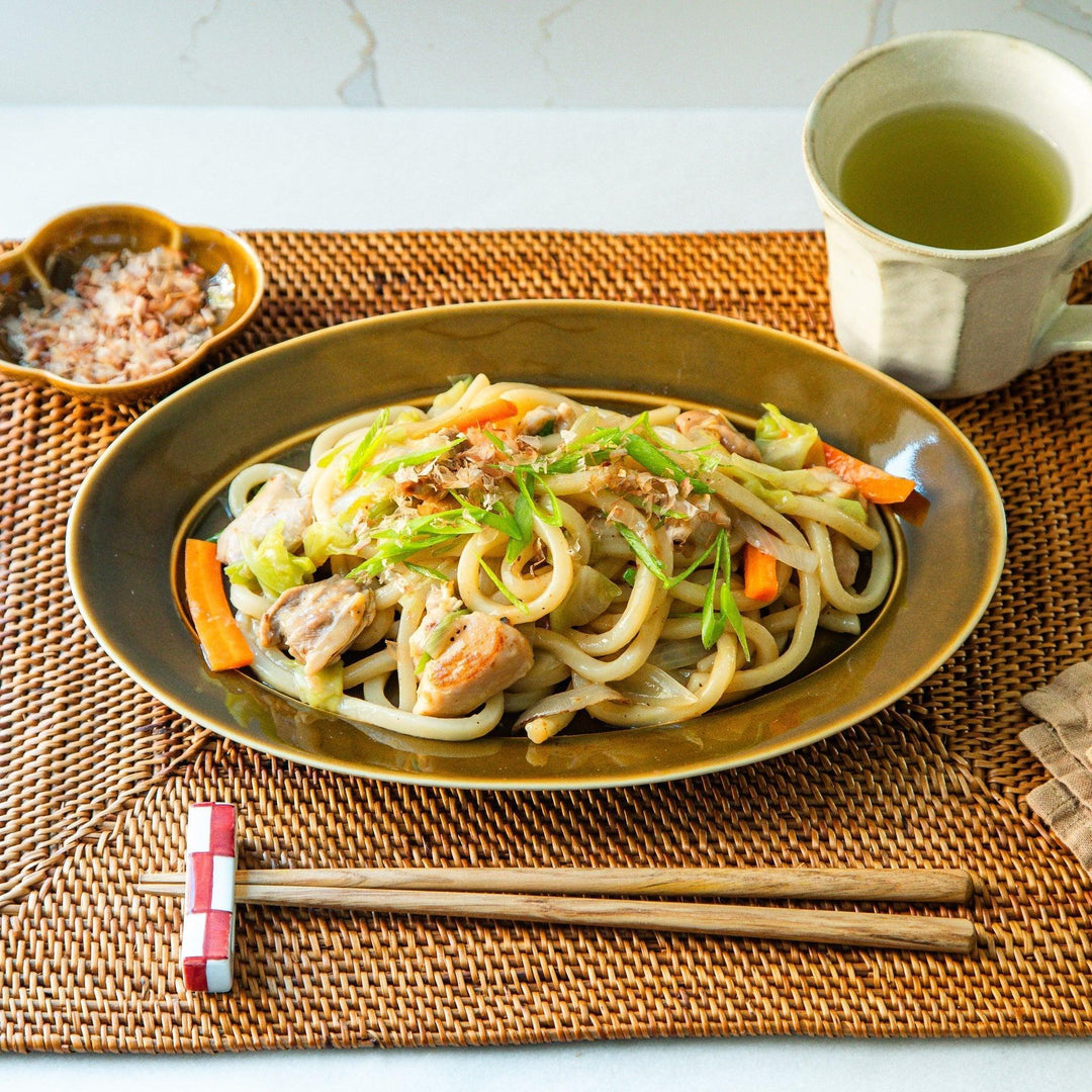 Sleek, dark brown or olive colored oval dinner plate with a glossy finish, simple and minimalist.
