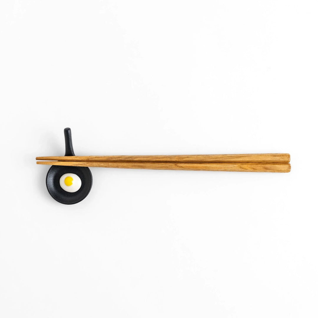 Frying pan chopstick rest with realistic fried egg design bringing playful touch to Japanese dining.