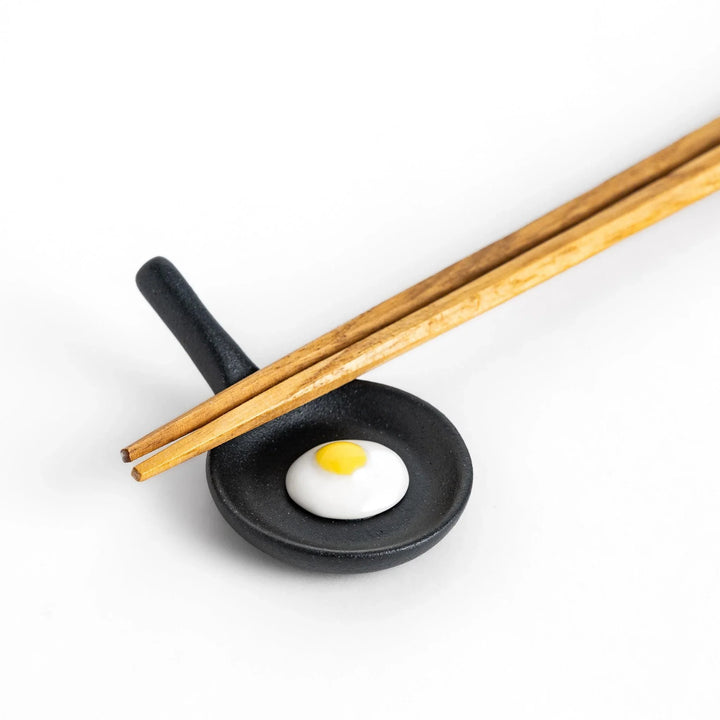 Frying pan chopstick rest with realistic fried egg design bringing playful touch to Japanese dining.
