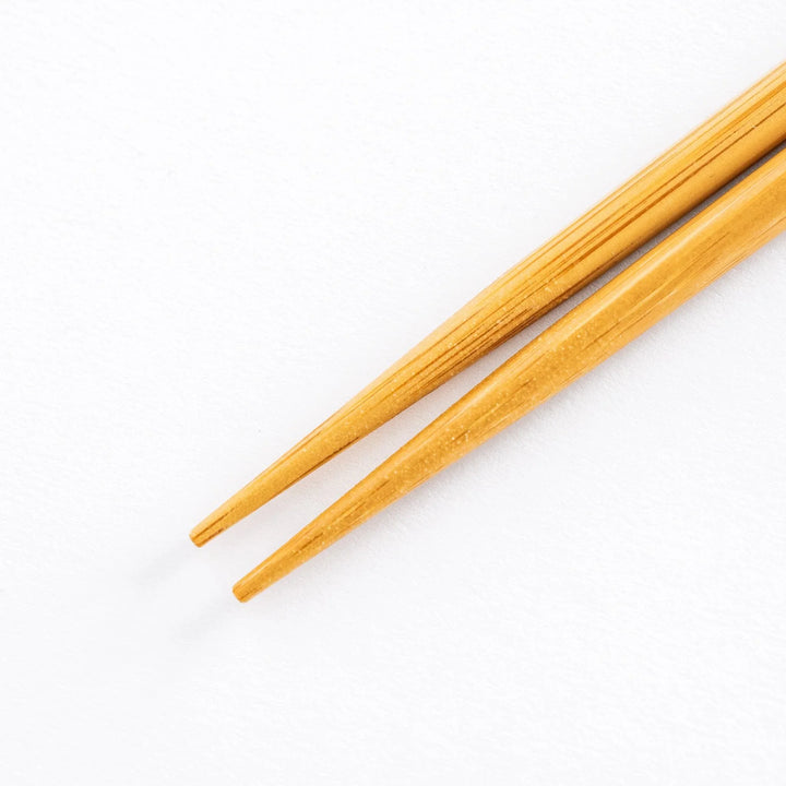Close-up of the sharp tips of beige bamboo cooking chopsticks, perfect for precise food handling.