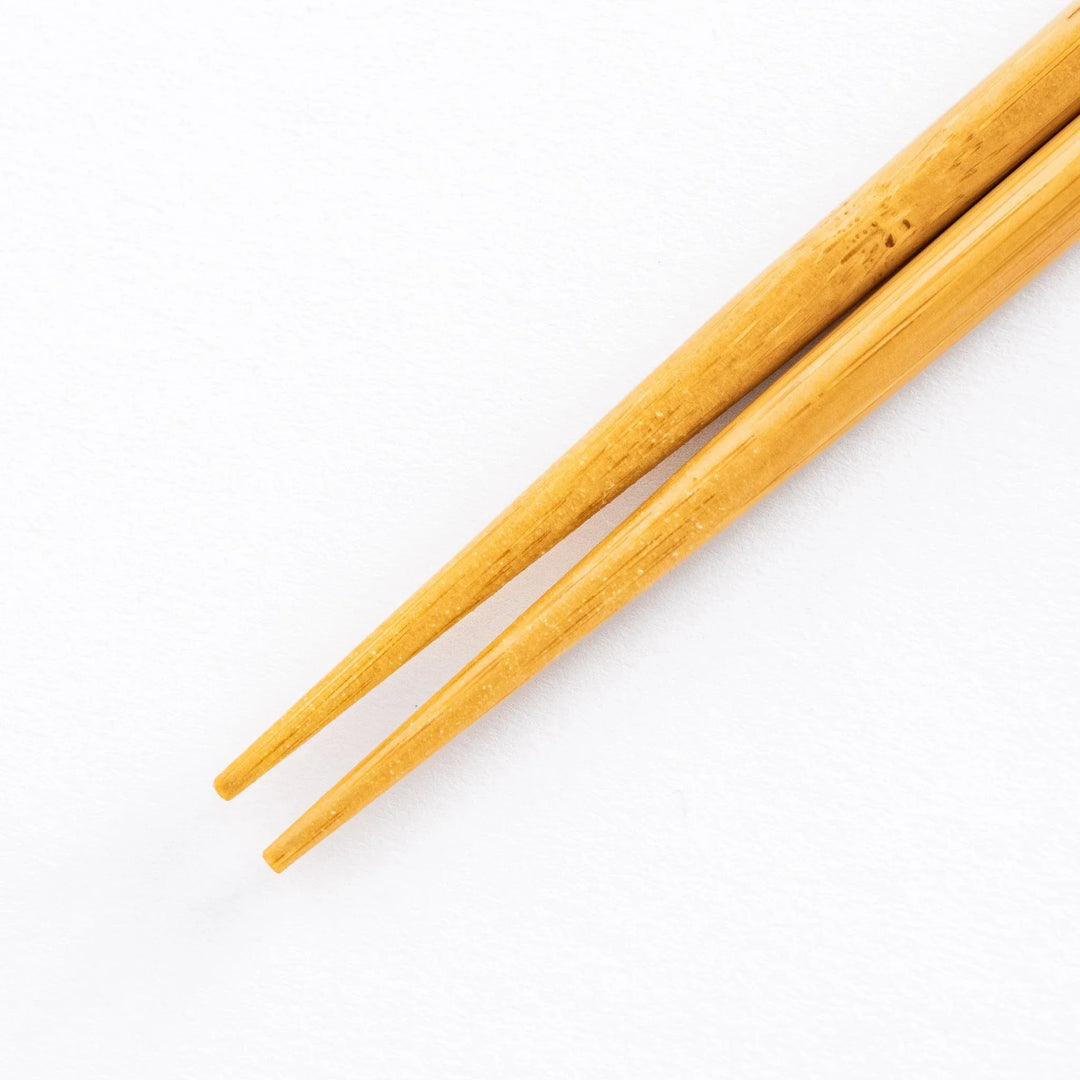 Close-up view of the bamboo tips of the cooking chopsticks, highlighting the tapered end for precision use.