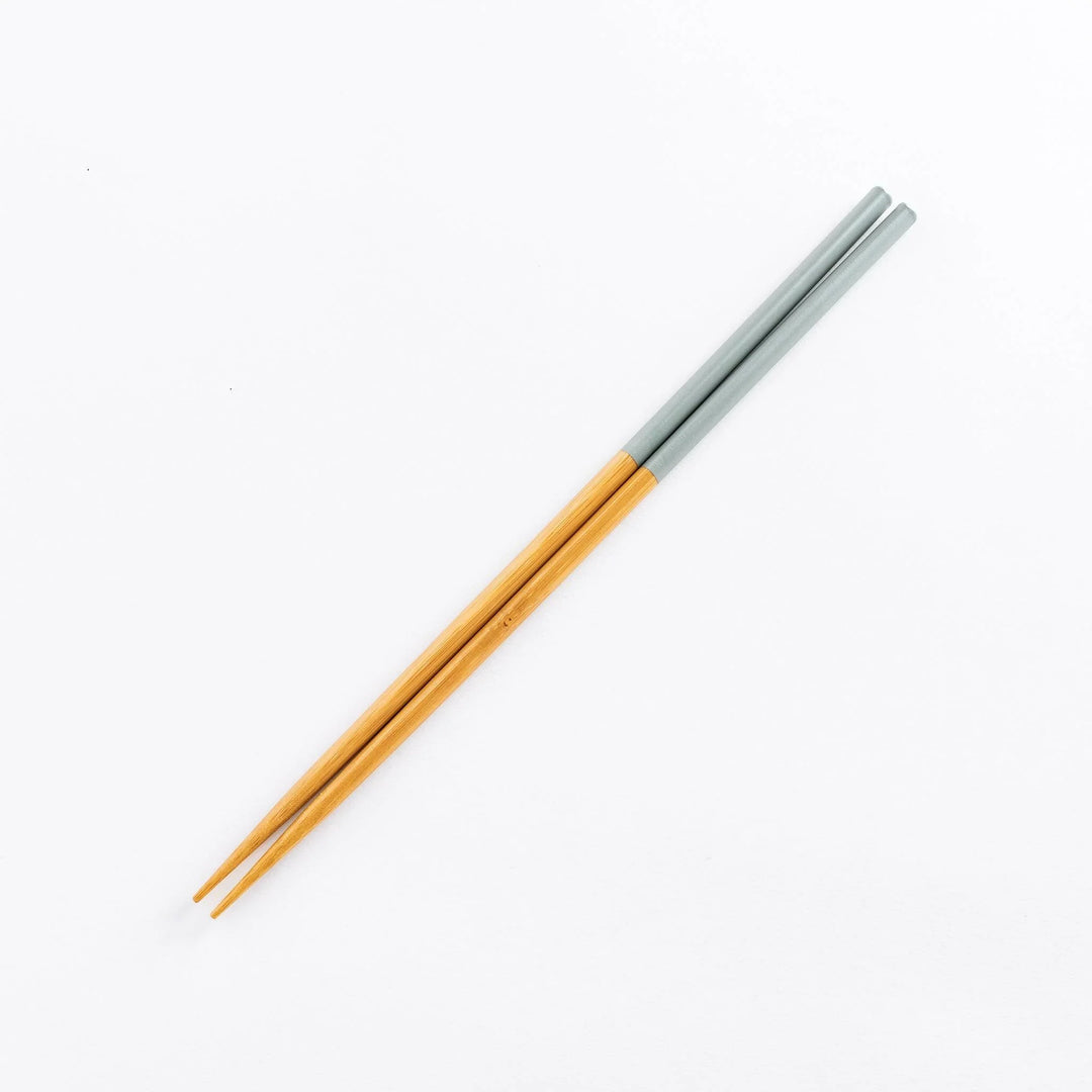 Light gray-handled cooking chopsticks with natural bamboo tips laid on a white background.