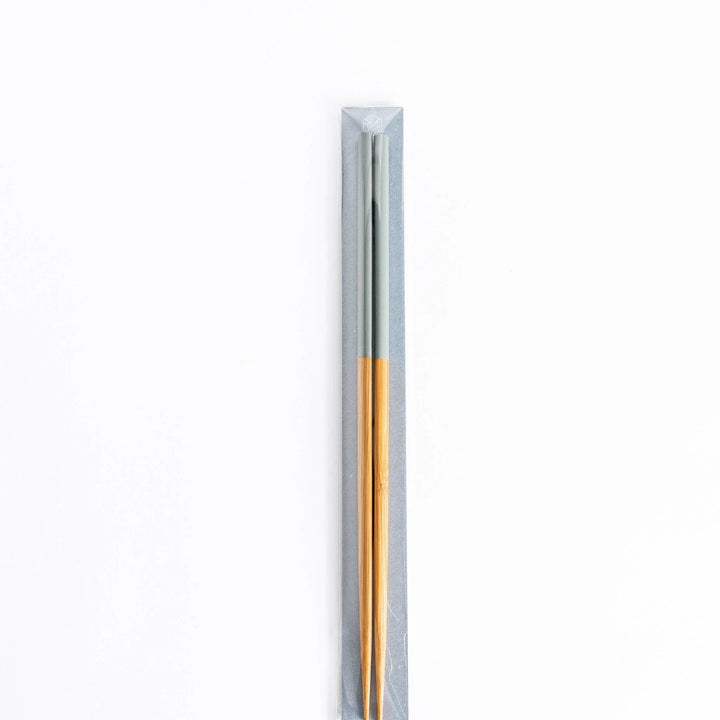 Packaged light gray and bamboo chopsticks, neatly displayed in a minimalist gray sleeve.