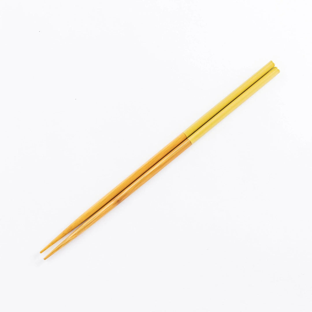 Wooden cooking chopsticks with a yellow-painted upper handle against a plain white background.