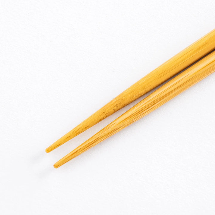 Close-up of the pointed wooden tips of cooking chopsticks on a white surface, highlighting natural wood grain.