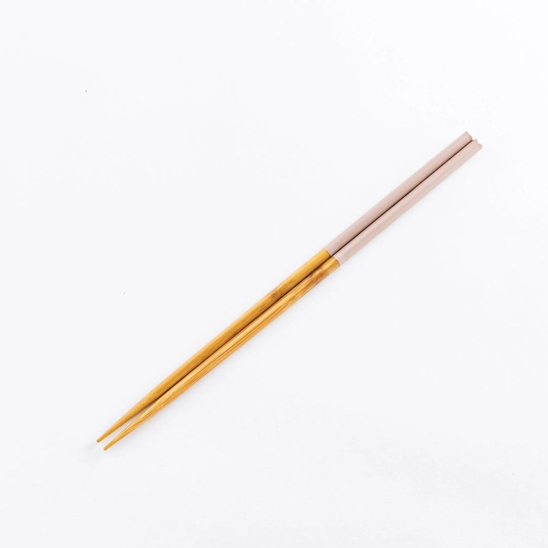 Chopsticks featuring light pink tips, with a natural bamboo finish on the rest of the length.
