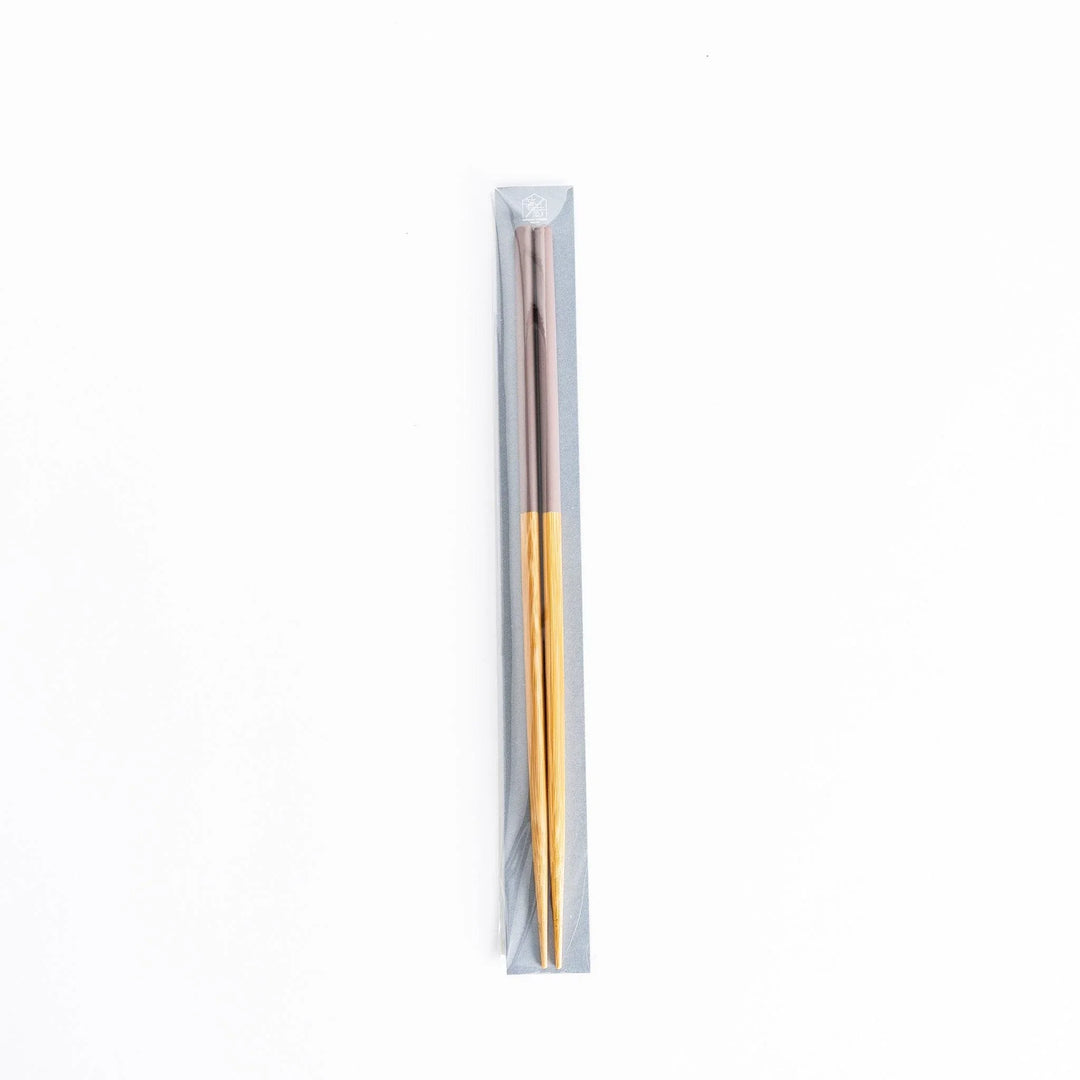 A single pair of cooking chopsticks in packaging, with bamboo shafts and rosybrown tips.