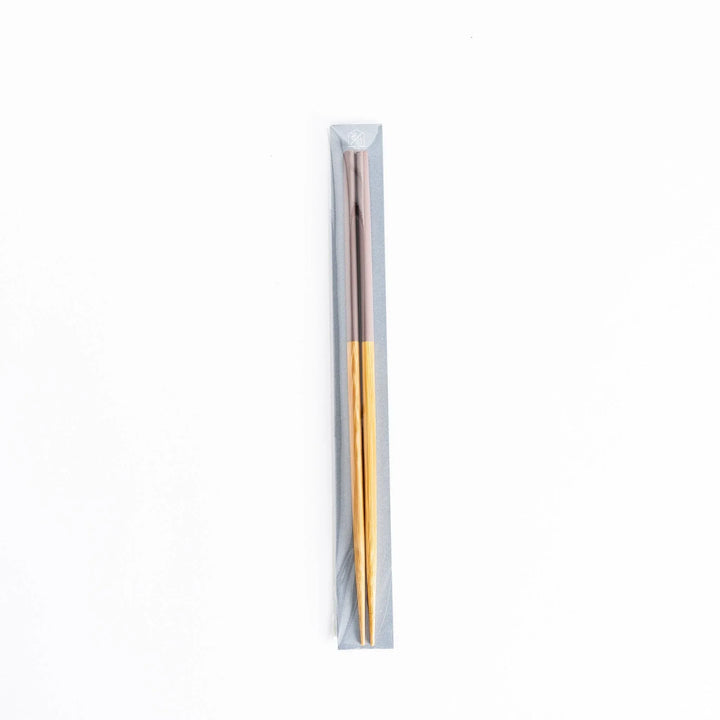 A single pair of cooking chopsticks in packaging, with bamboo shafts and rosybrown tips.