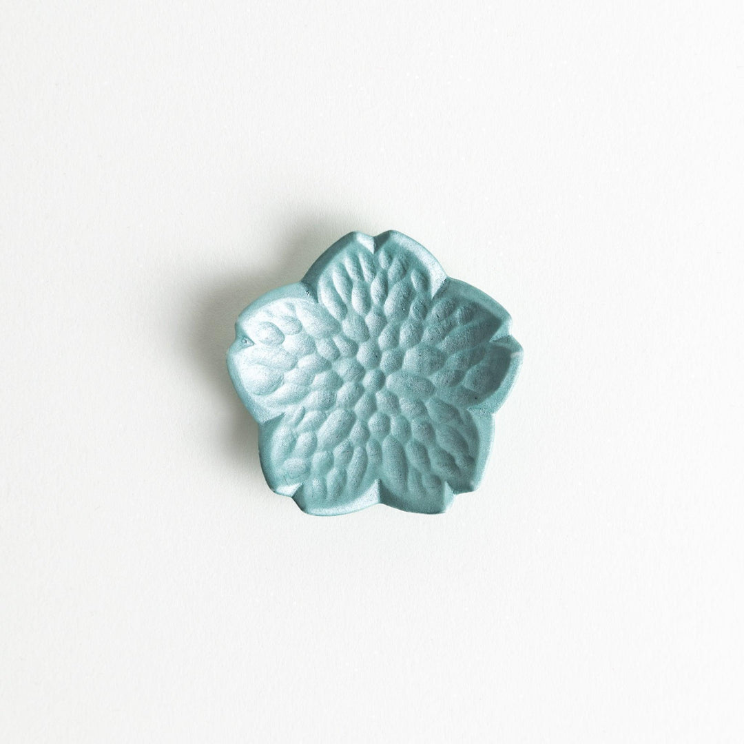 Small flower shaped chopstick rests in yellow blue white and pink arranged neatly on wooden surface.