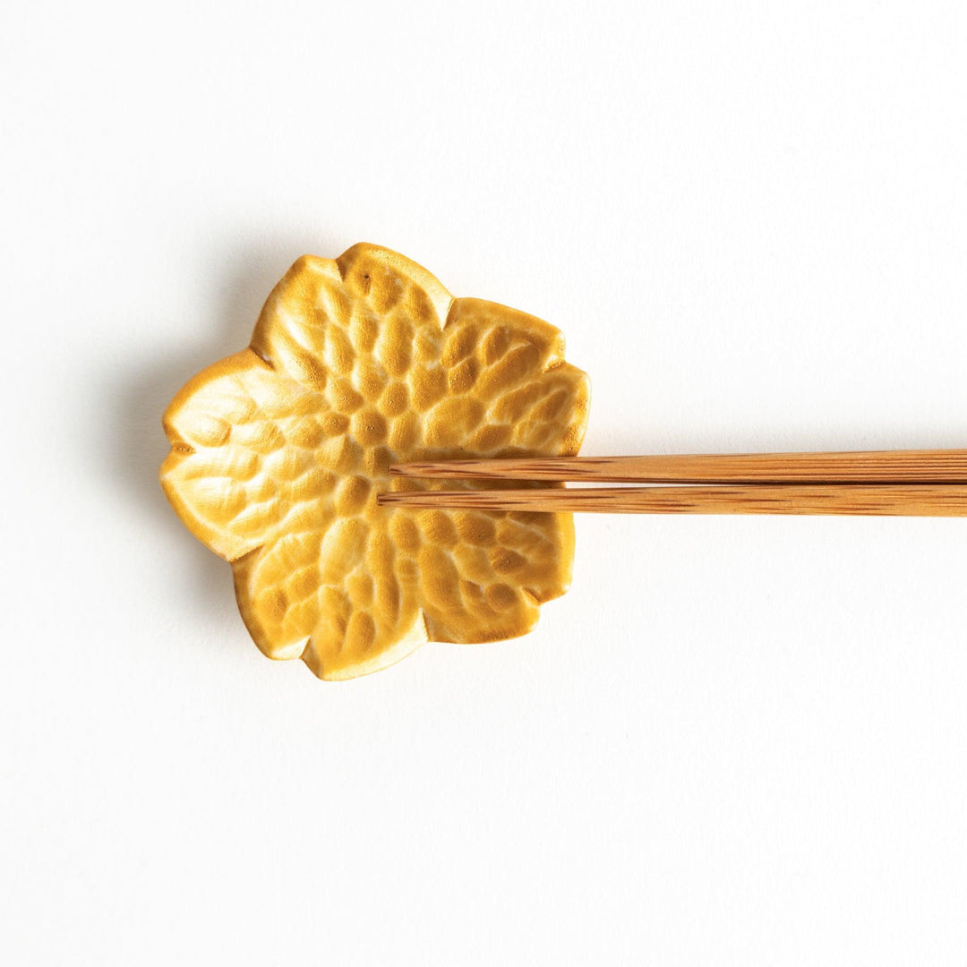 Small flower shaped chopstick rests in yellow blue white and pink arranged neatly on wooden surface.