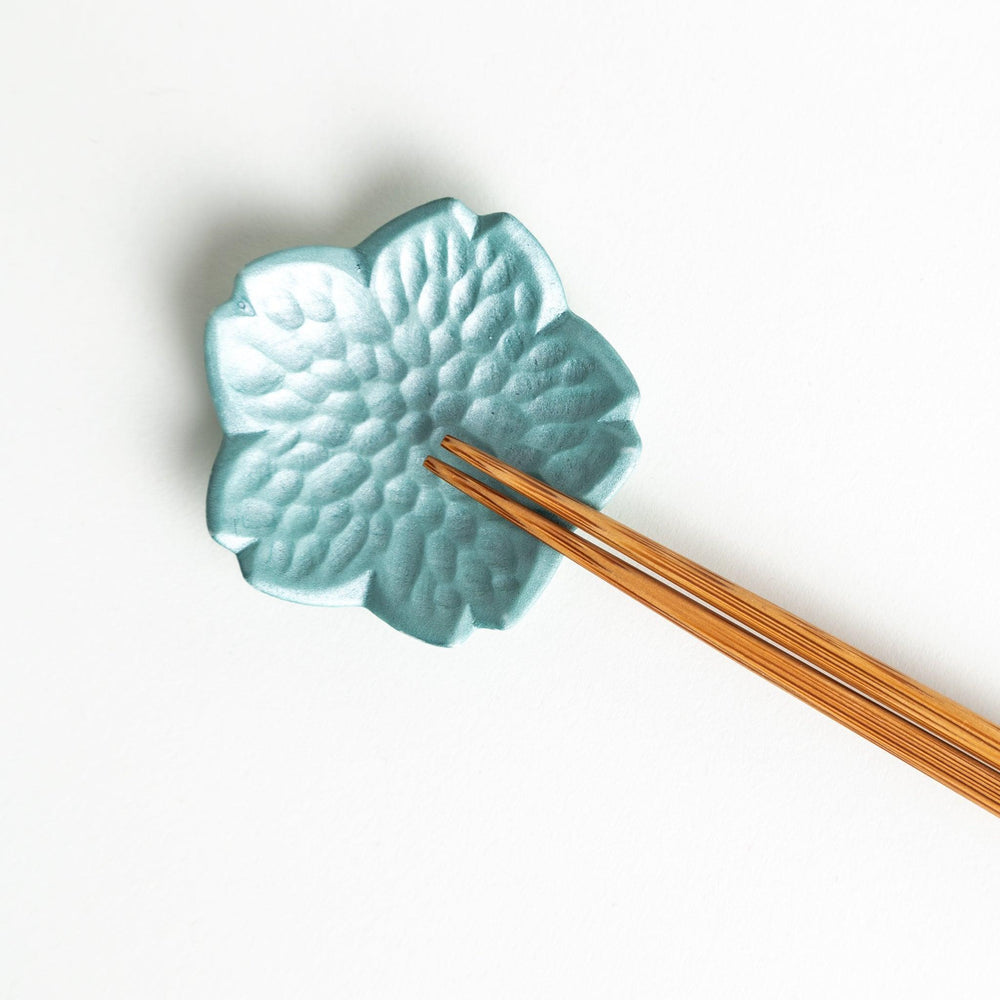 Small flower shaped chopstick rests in yellow blue white and pink arranged neatly on wooden surface.