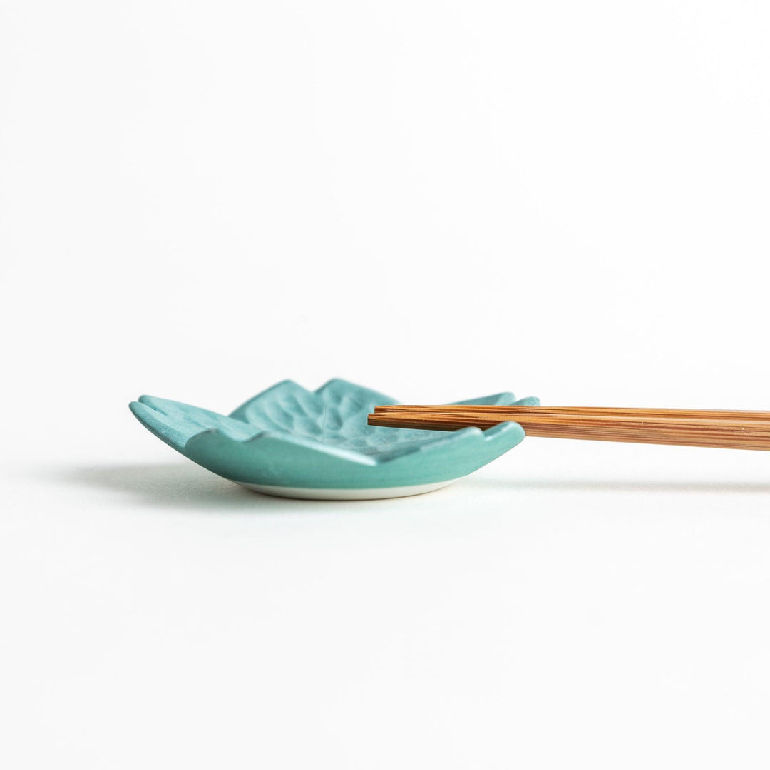 Small flower shaped chopstick rests in yellow blue white and pink arranged neatly on wooden surface.