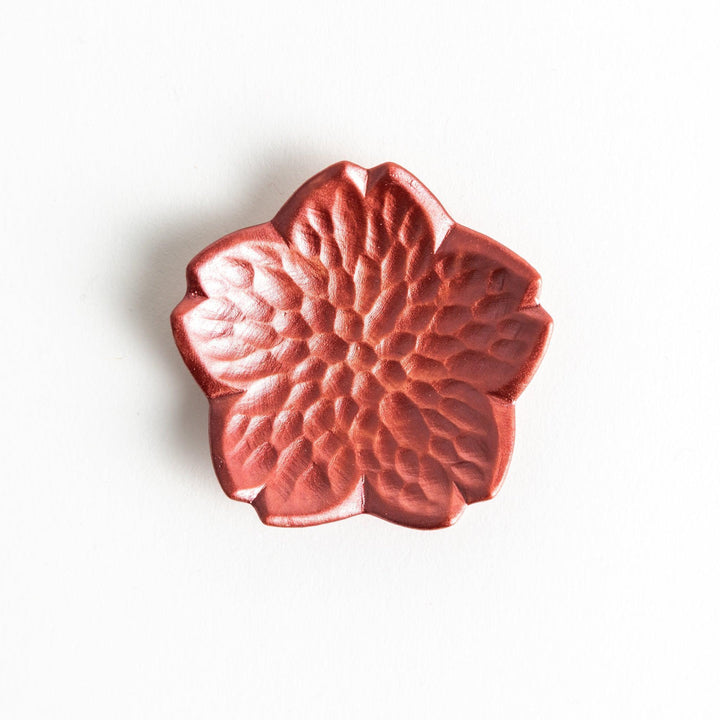 Small flower shaped chopstick rests in yellow blue white and pink arranged neatly on wooden surface.