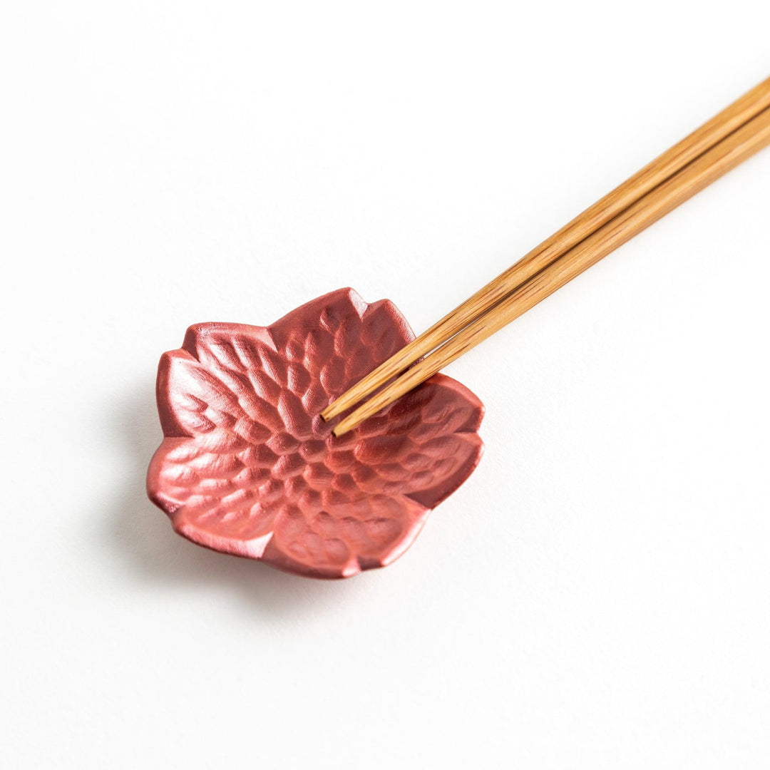 Small flower shaped chopstick rests in yellow blue white and pink arranged neatly on wooden surface.