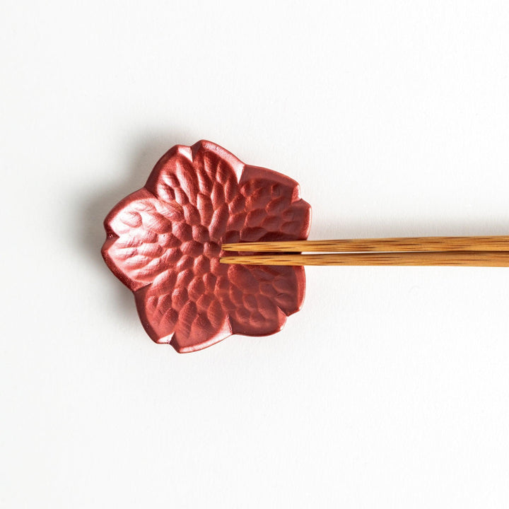 Small flower shaped chopstick rests in yellow blue white and pink arranged neatly on wooden surface.