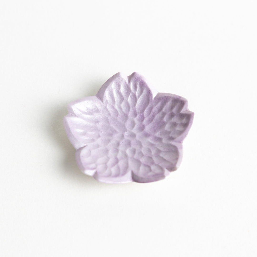 Small flower shaped chopstick rests in yellow blue white and pink arranged neatly on wooden surface.