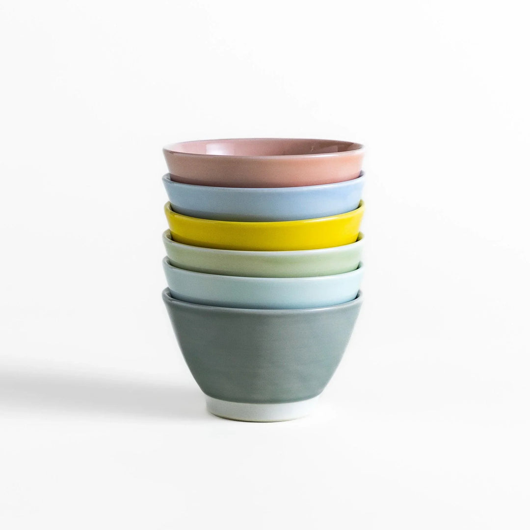 Stack of six pastel Japanese dessert bowls in pink blue yellow green white and gray with smooth finish.