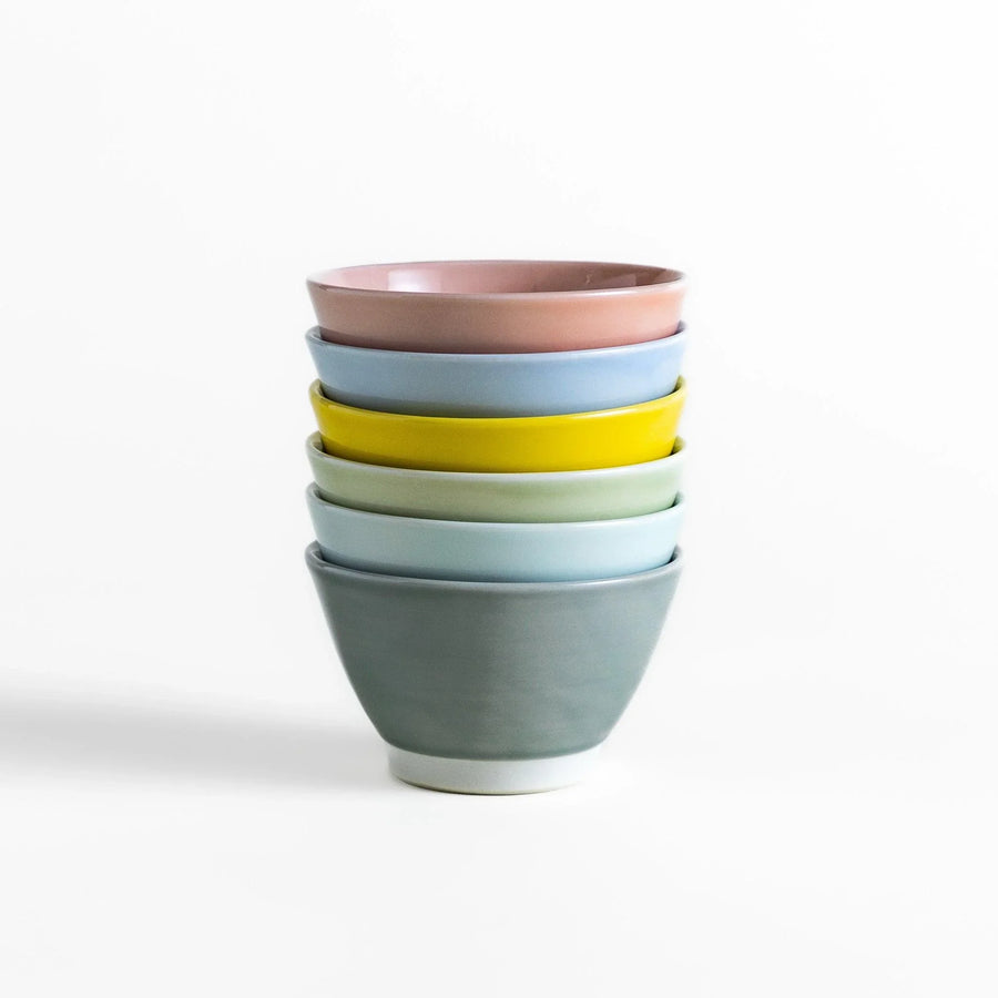 Stack of six pastel Japanese dessert bowls in pink blue yellow green white and gray with smooth finish.