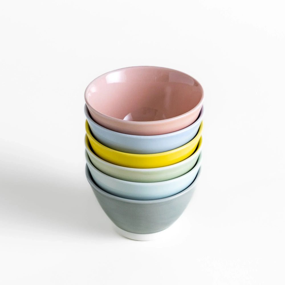 Stack of six pastel Japanese dessert bowls in pink blue yellow green white and gray with smooth finish.