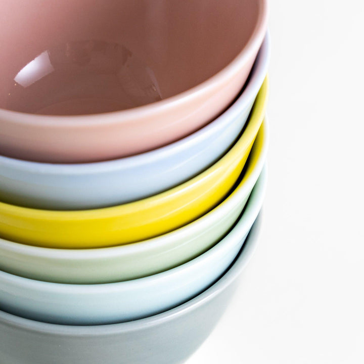 Stack of six pastel Japanese dessert bowls in pink blue yellow green white and gray with smooth finish.