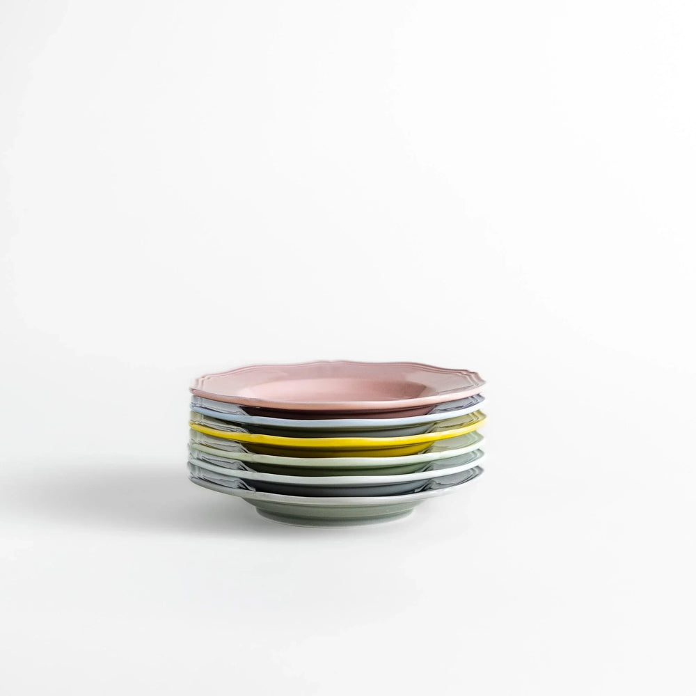 Stack of pastel Japanese ceramic dessert plates in soft hues with scalloped edges, adding charm and color to everyday dining