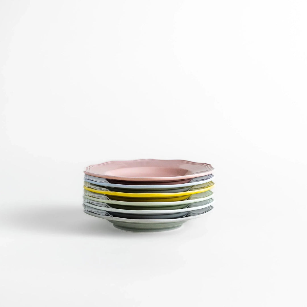 Stack of pastel Japanese ceramic dessert plates in soft hues with scalloped edges, adding charm and color to everyday dining