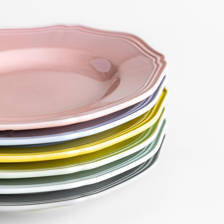 Stack of pastel Japanese ceramic dessert plates in soft hues with scalloped edges, adding charm and color to everyday dining