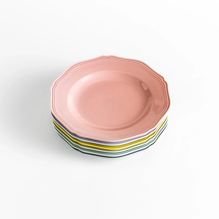 Stack of pastel ceramic dinner plates with scalloped edges in soft hues, combining everyday charm with refined design