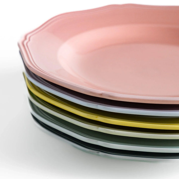 Stack of pastel ceramic dinner plates with scalloped edges in soft hues, combining everyday charm with refined design
