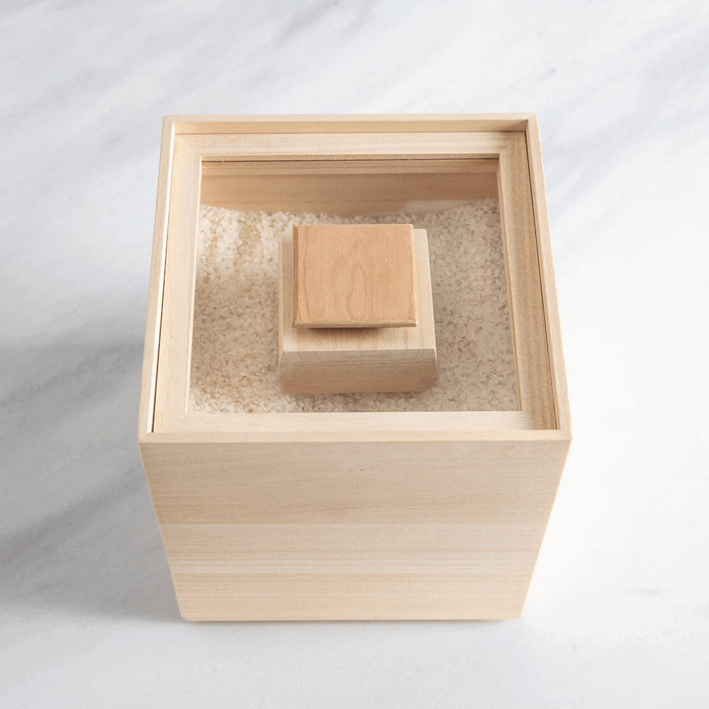 Paulownia wood rice container with inner lid, filled with rice for traditional Japanese kitchen storage.