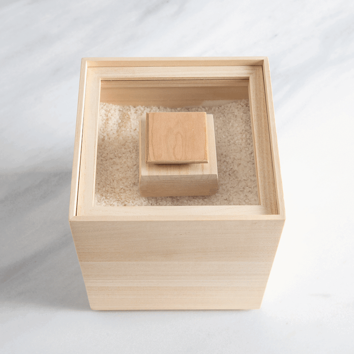 Paulownia wood rice container with inner lid, filled with rice for traditional Japanese kitchen storage.
