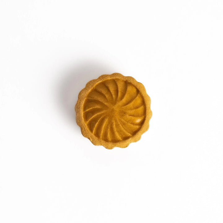 Pear tart shaped chopstick rest with swirled top and beige tone adding sweet charm to dining table.