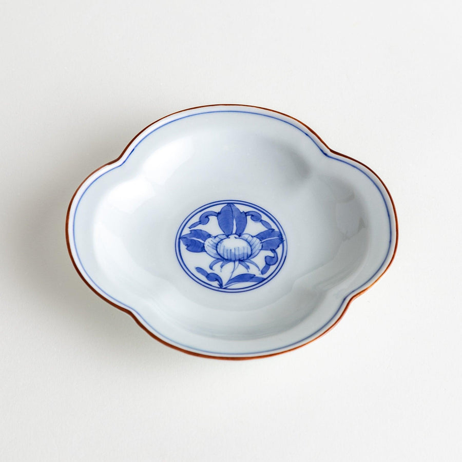 A blue and white porcelain dish with a floral motif in the center, shaped like a cloud.