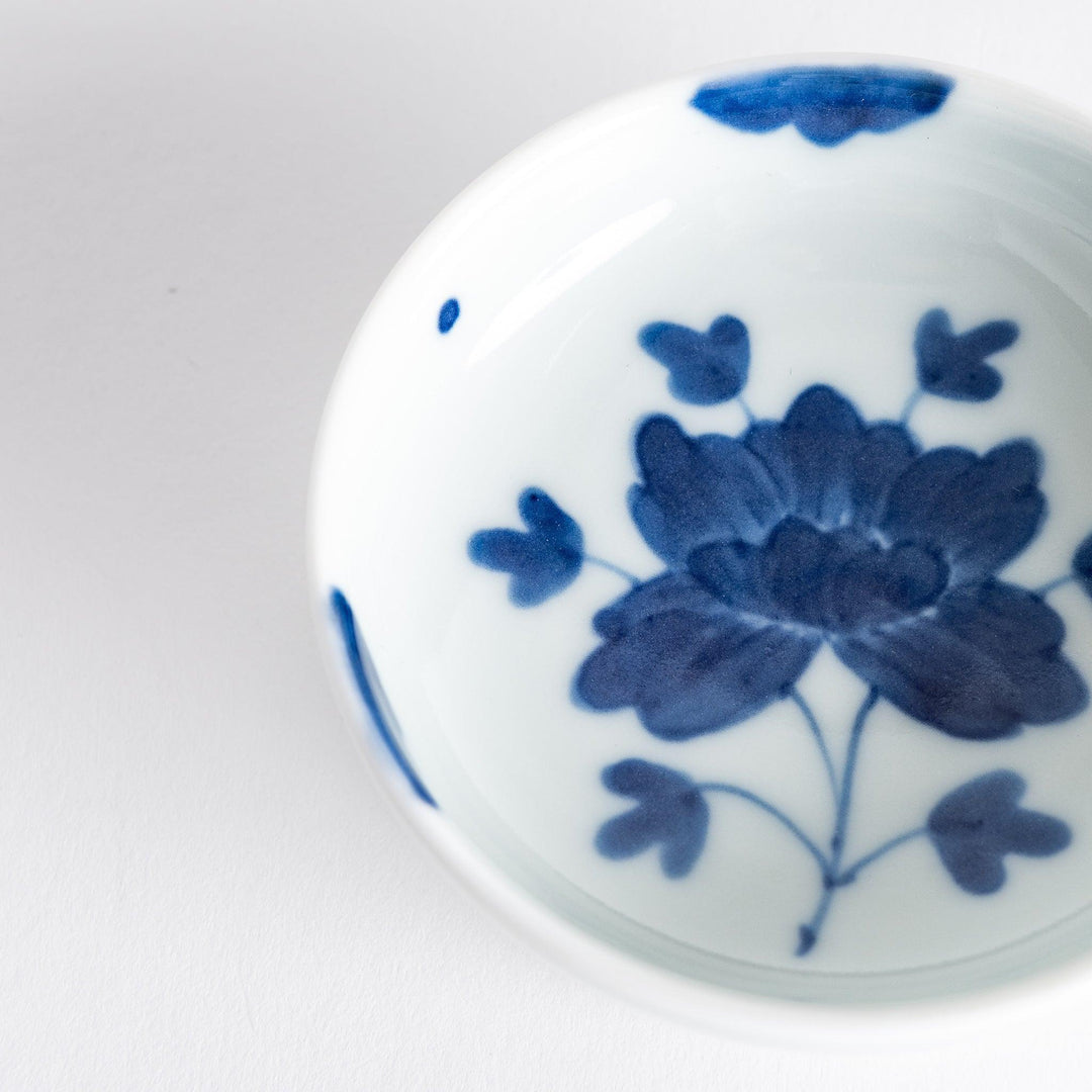 White raised sauce dish featuring a hand-painted blue peony flower.