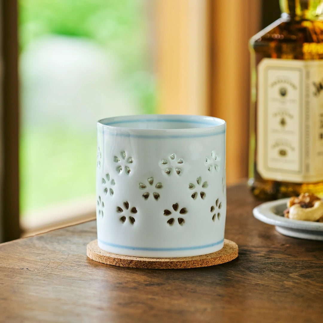 Petal Crystal Rocks Glass filled with whiskey, with sakura cutouts appearing dark in the soft afternoon light.