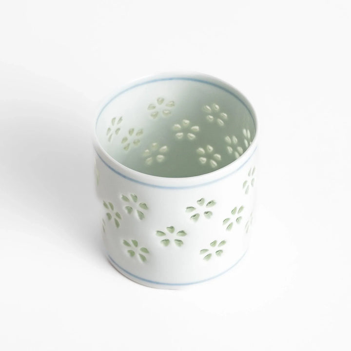 Unique ceramic glass featuring a delicate cut-out floral design, perfect for adding a touch of elegance to any table.