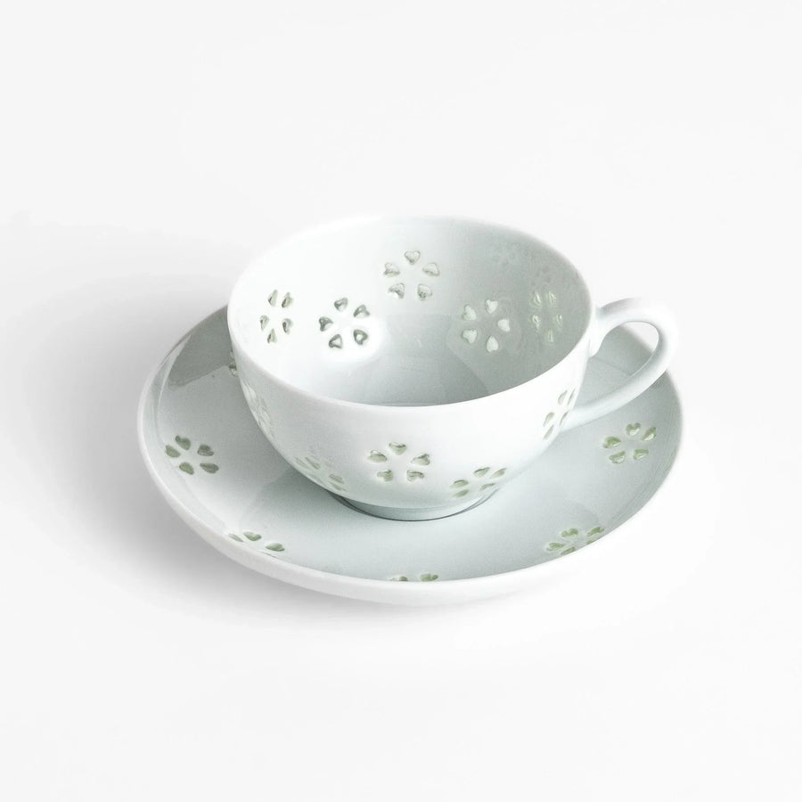 Japanese teacup and saucer set with petal cutouts in pale green and white porcelain for soft elegant look.