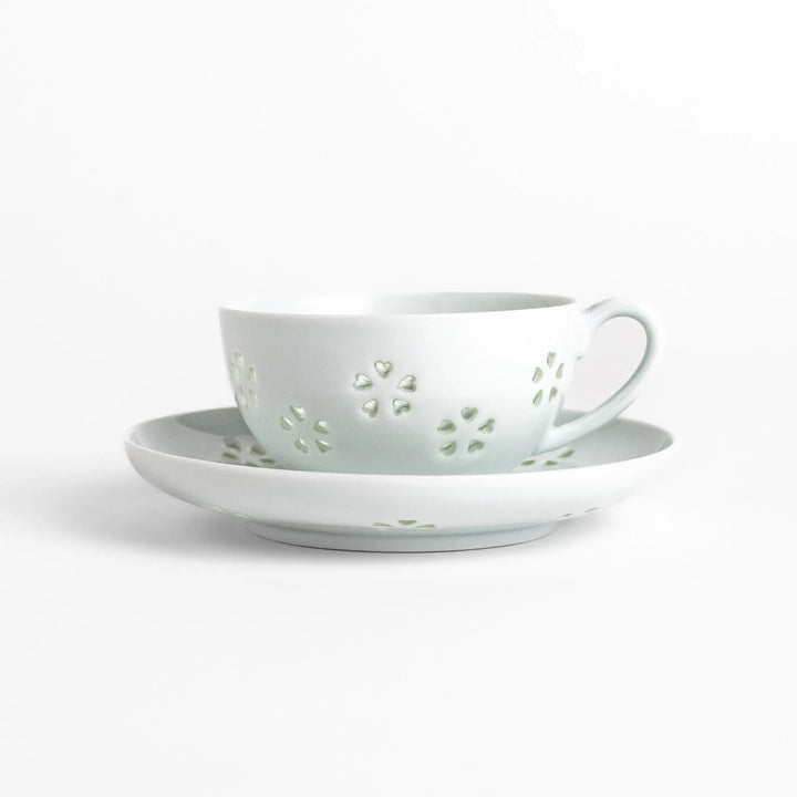 Japanese teacup and saucer set with petal cutouts in pale green and white porcelain for soft elegant look.