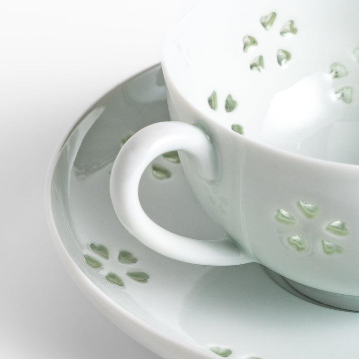 Japanese teacup and saucer set with petal cutouts in pale green and white porcelain for soft elegant look.
