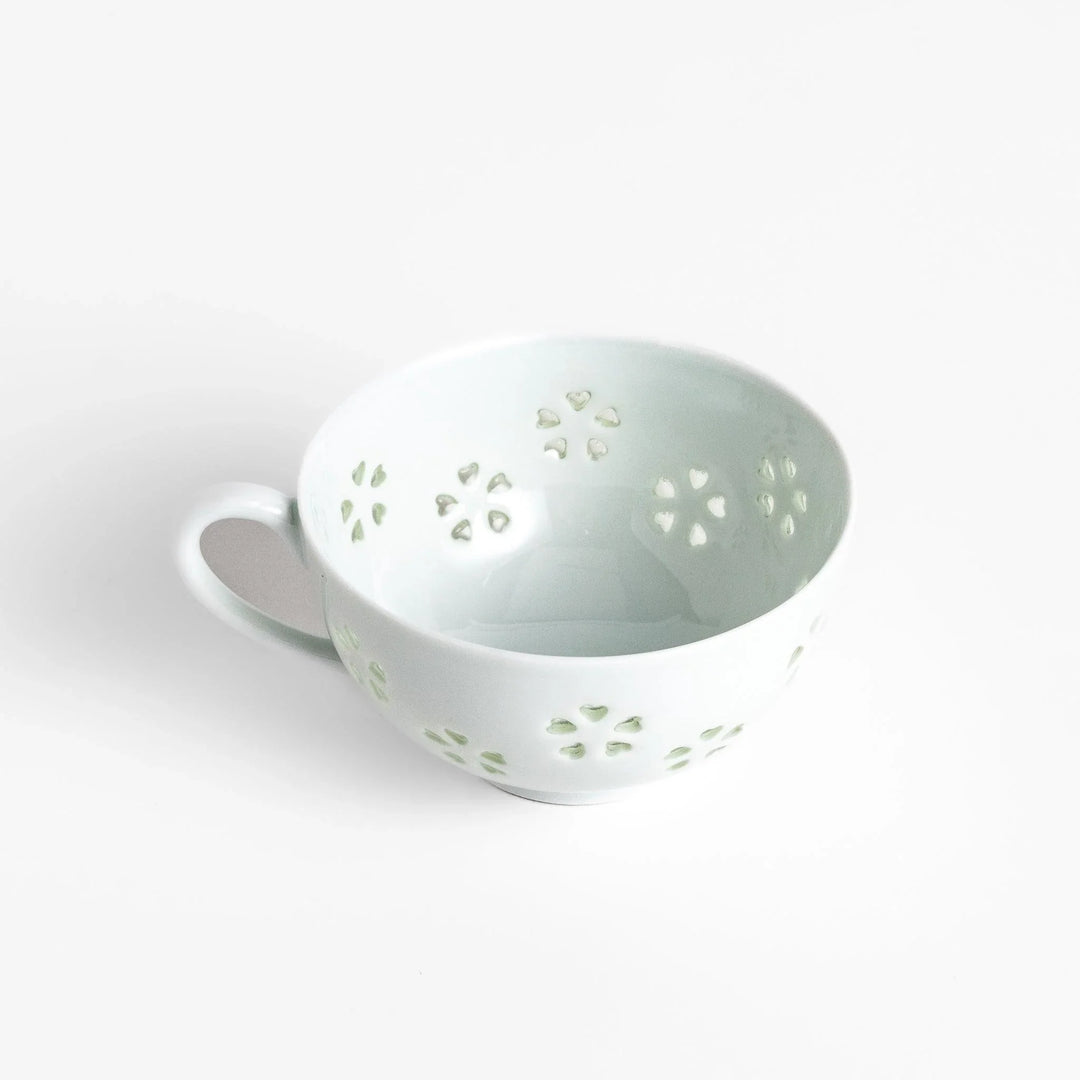 Japanese teacup and saucer set with petal cutouts in pale green and white porcelain for soft elegant look.