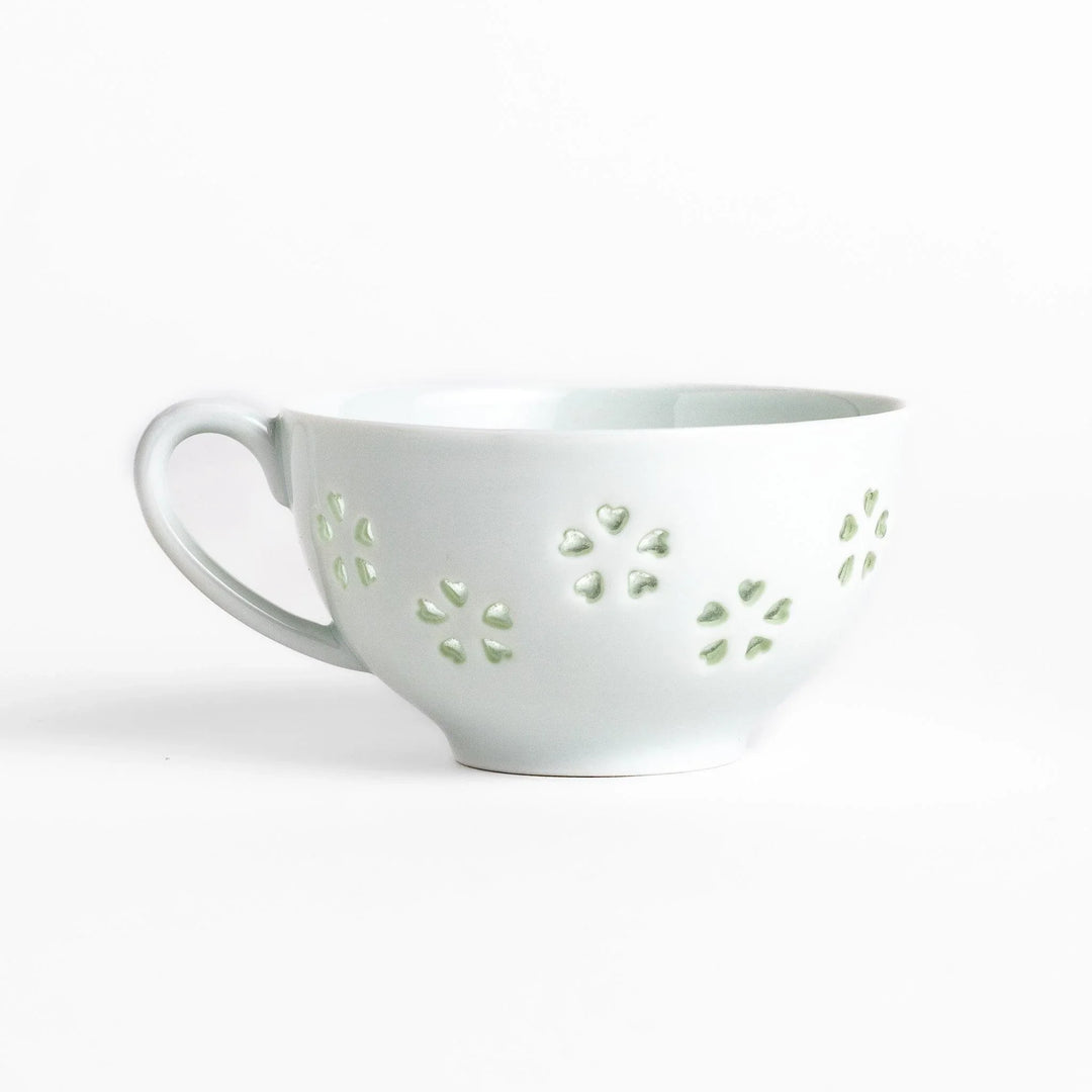 Japanese teacup and saucer set with petal cutouts in pale green and white porcelain for soft elegant look.