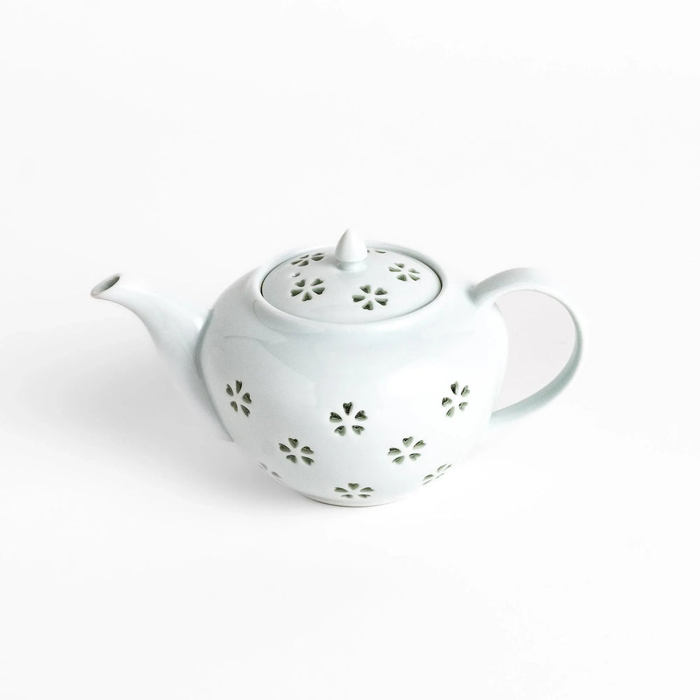 Elegant Japanese porcelain teapot with petal cutouts pointed lid and smooth handle for refined tea time.