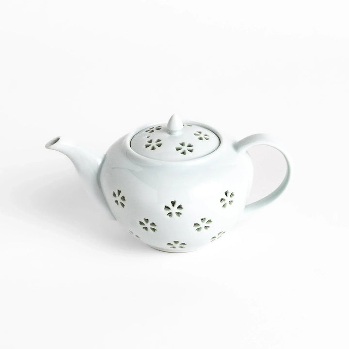 Elegant Japanese porcelain teapot with petal cutouts pointed lid and smooth handle for refined tea time.