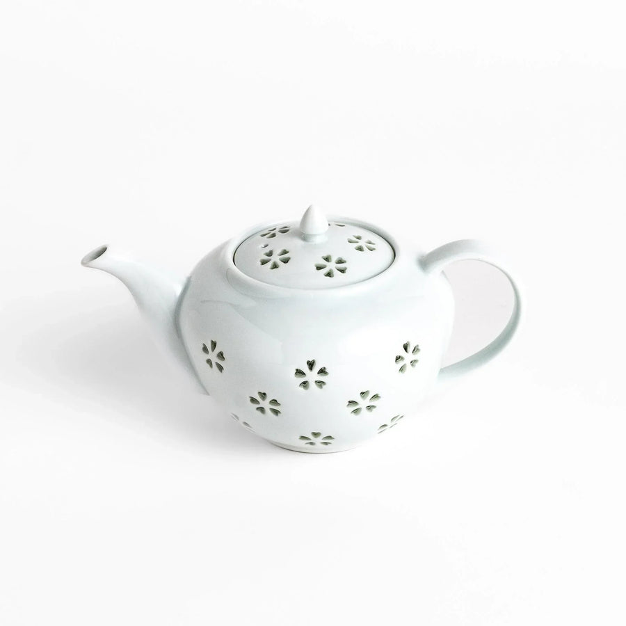 Elegant Japanese porcelain teapot with petal cutouts pointed lid and smooth handle for refined tea time.