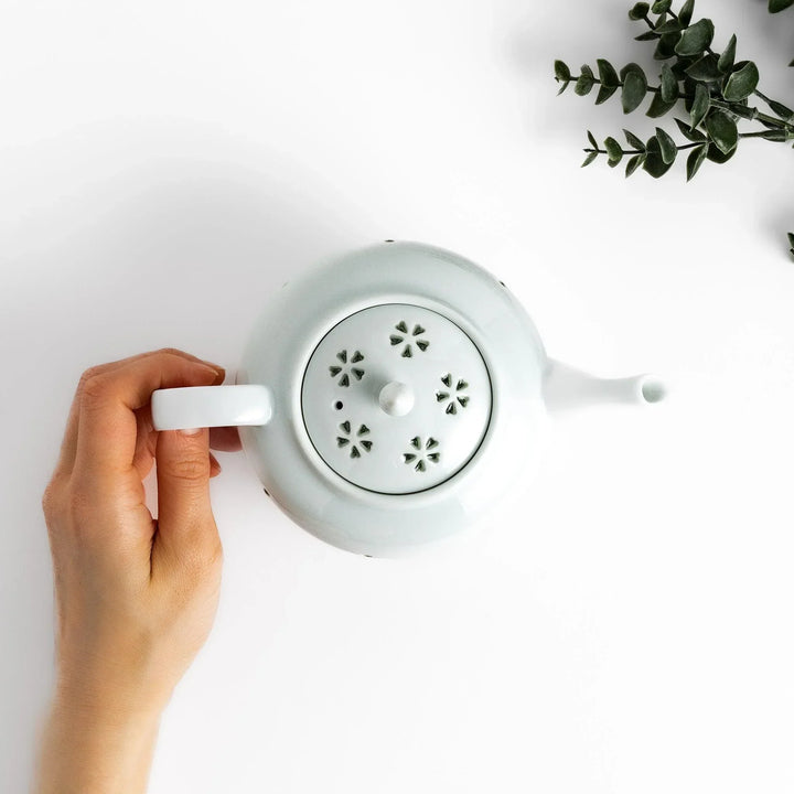 Elegant Japanese porcelain teapot with petal cutouts pointed lid and smooth handle for refined tea time.